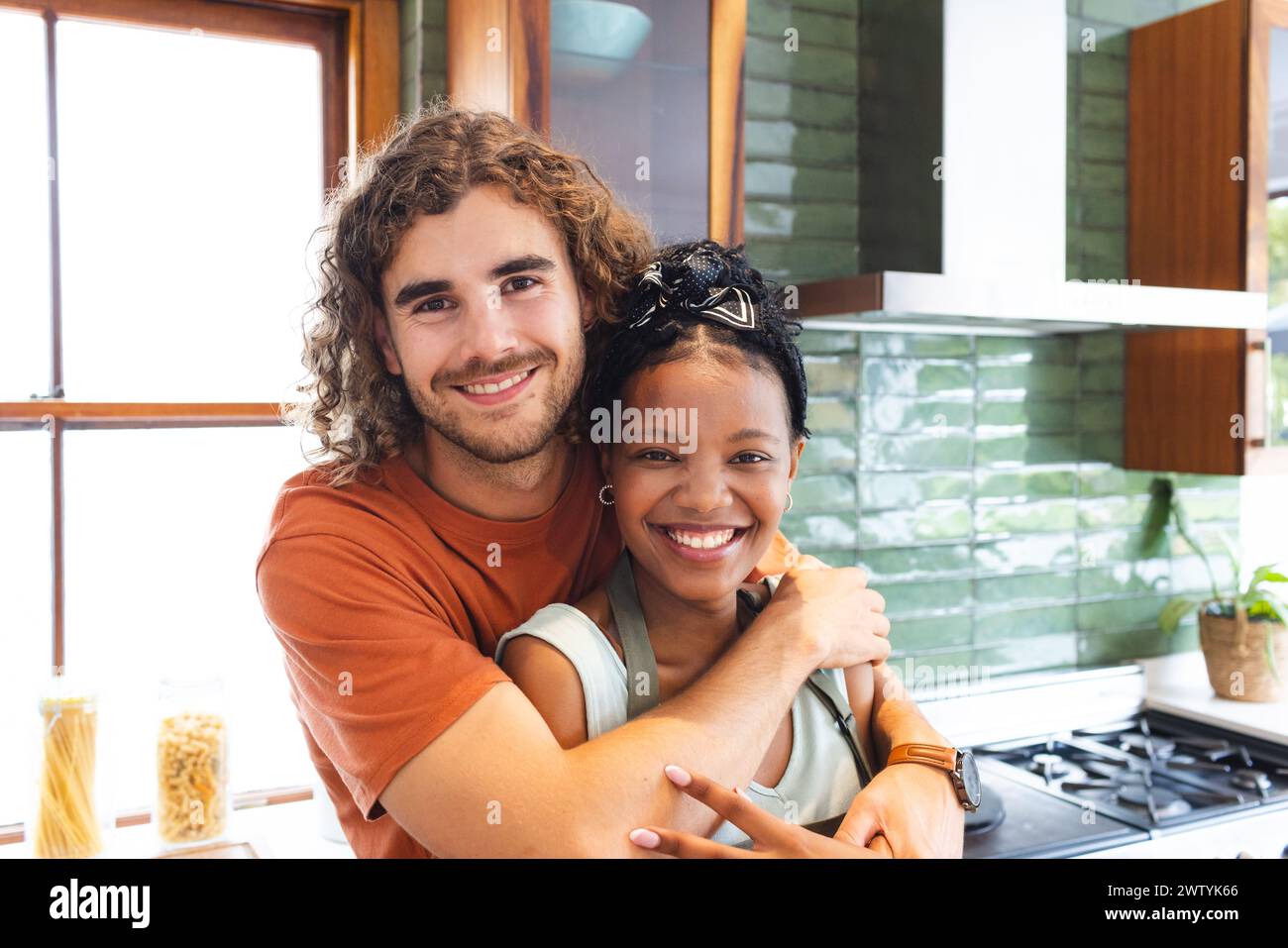 Un couple diversifié partage une étreinte chaleureuse dans une cuisine moderne à la maison Banque D'Images