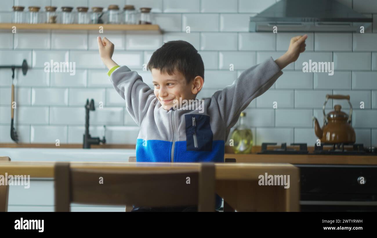 Petit garçon d'âge préscolaire est venu avec un plan créatif, se sent excité par la bonne idée, motivation d'inspiration tout en étant assis dans la cuisine à la maison. Banque D'Images