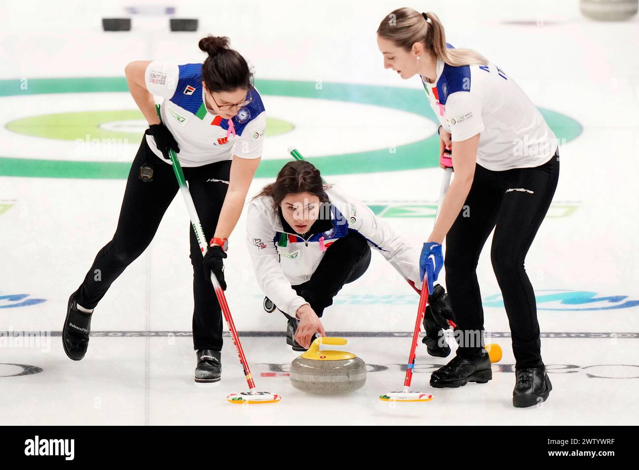 Italy's skip Stefania Constantini delivers a stone as teammates Angela Romei, left, and Elena Mathis, right, prepare to sweep against South Korea during the women's World Curling Championships in Sydney, Nova Scotia Wednesday, March 20, 2024. (Darren Calabrese/The Canadian Press via AP) Banque D'Images