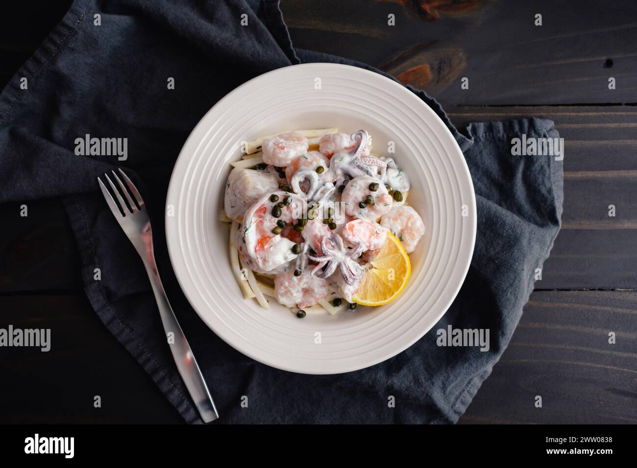 Salade de fruits de mer pochés servie sur une remoulade de racine de céleri : bol de crevettes, calmars et noix de Saint-Jacques avec sauce à l'aneth au citron servi sur une remoulade de céleri-rave Banque D'Images