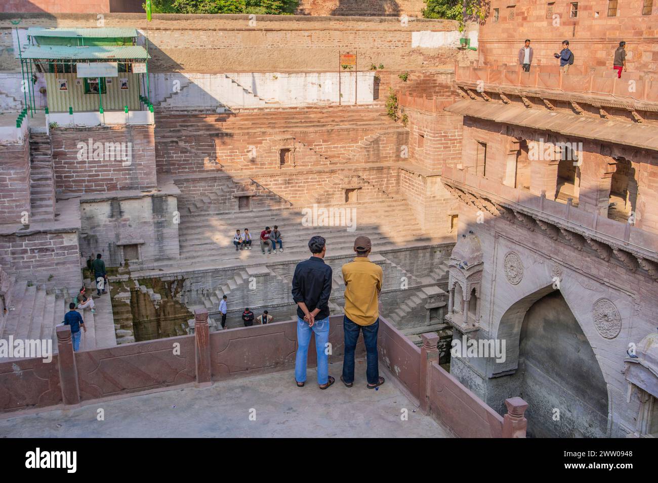 Jodhpur, Rajasthan, Inde - 17 décembre 2023 : deux hommes sur les marches architecturales antiques appelées Toorji Ka Jhalra Bavdi dans la ville bleue de jodhpur Banque D'Images