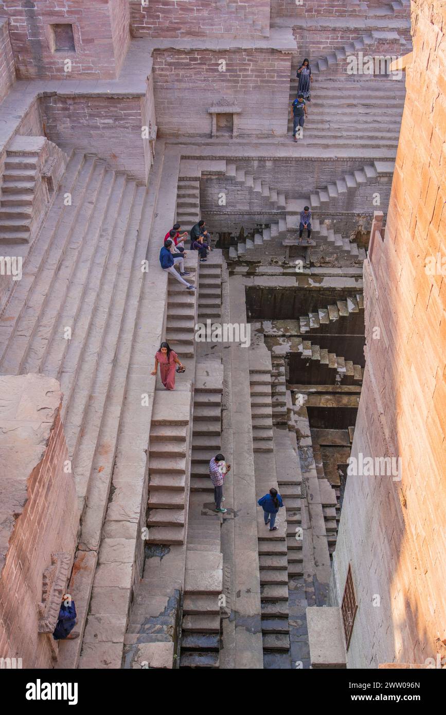 Jodhpur, Rajasthan, Inde - décembre 2023 : les gens assis sur les anciennes marches architecturales appelées Toorji Ka Jhalra Bavdi dans la ville bleue de jodhpur Banque D'Images