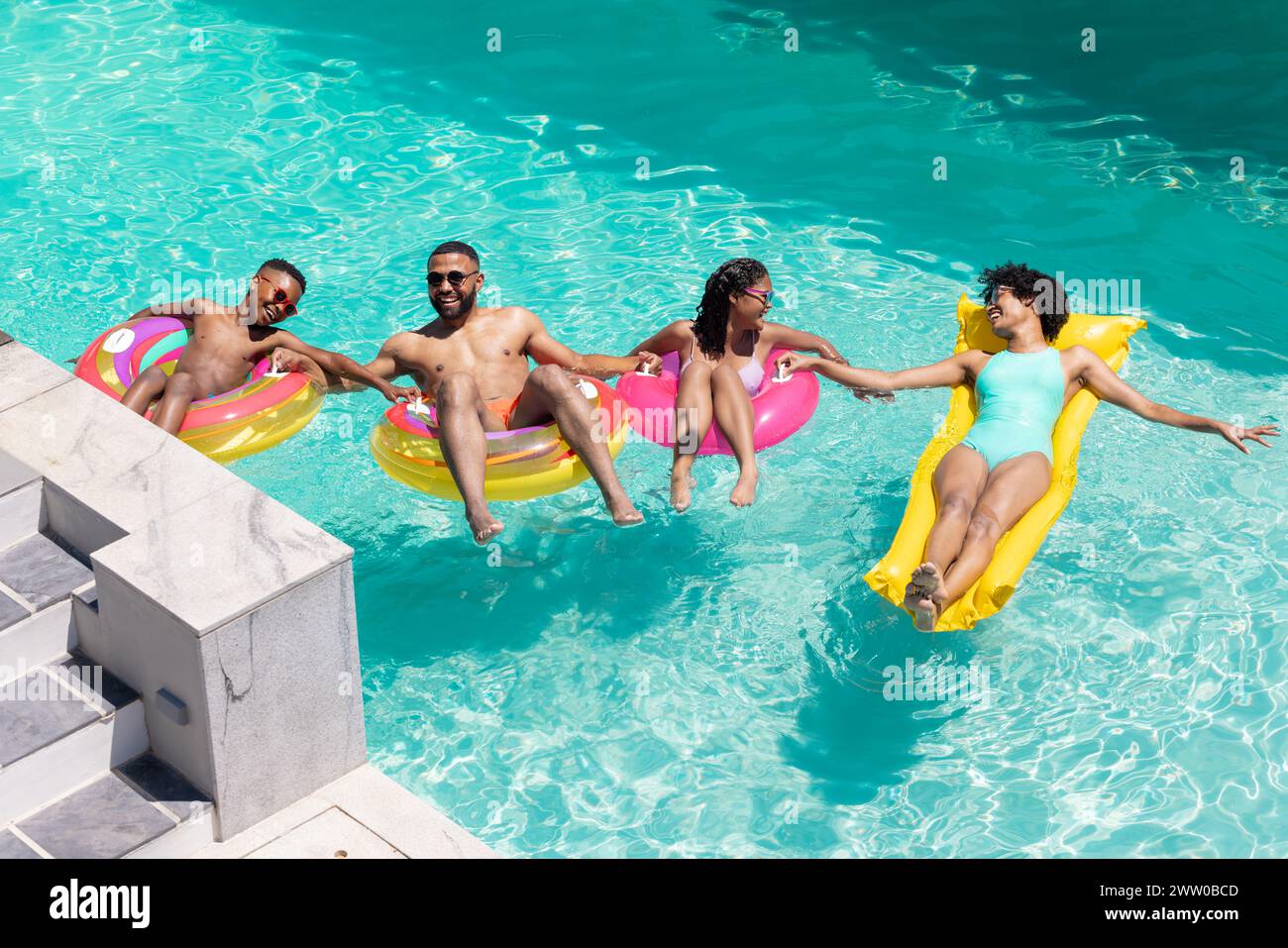 Une famille afro-américaine profite d'une journée ensoleillée flottant dans une piscine Banque D'Images
