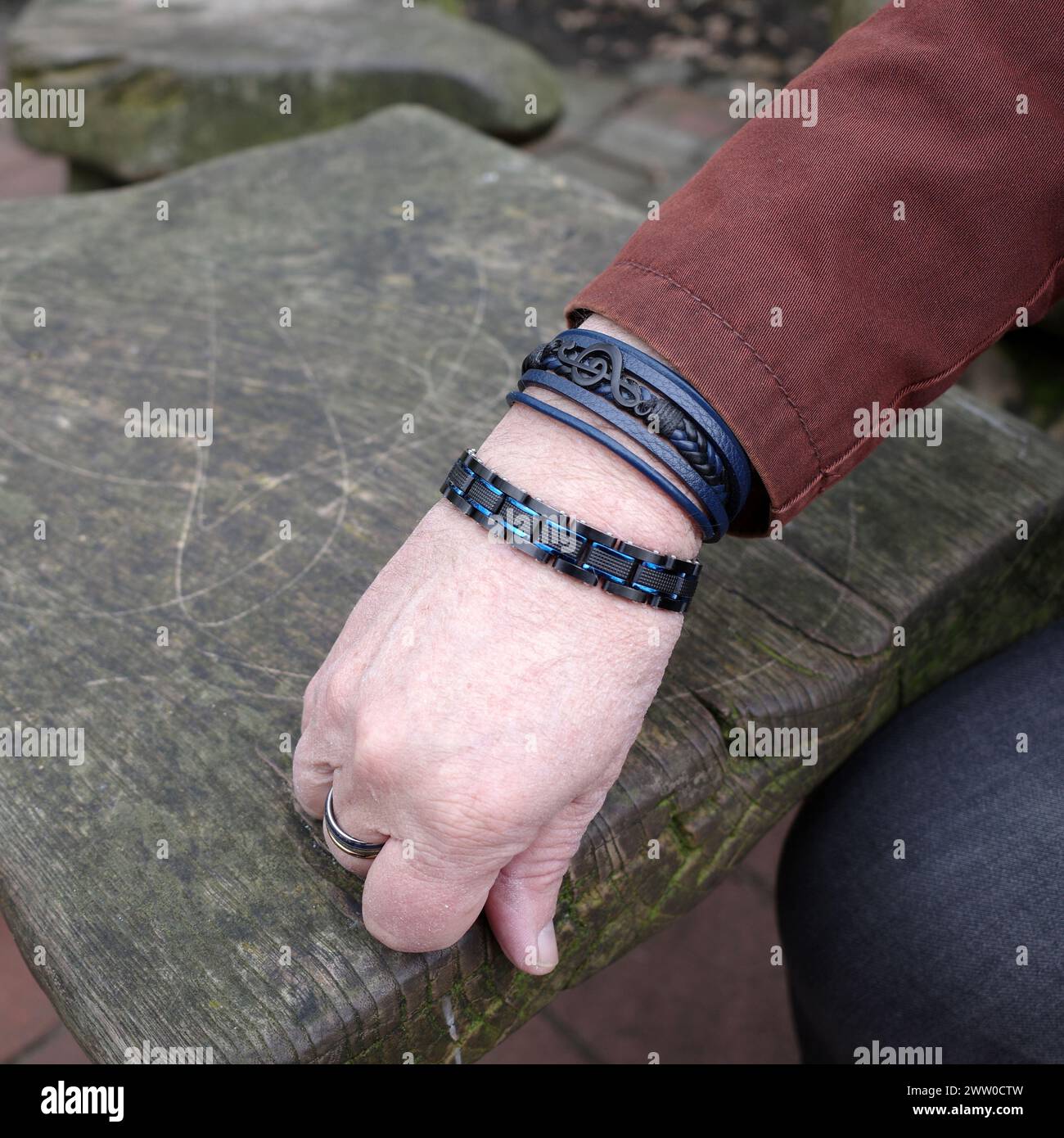 La main d'un musicien à la mode avec des bracelets noirs. Un bracelet contient une clef musicale. Banque D'Images