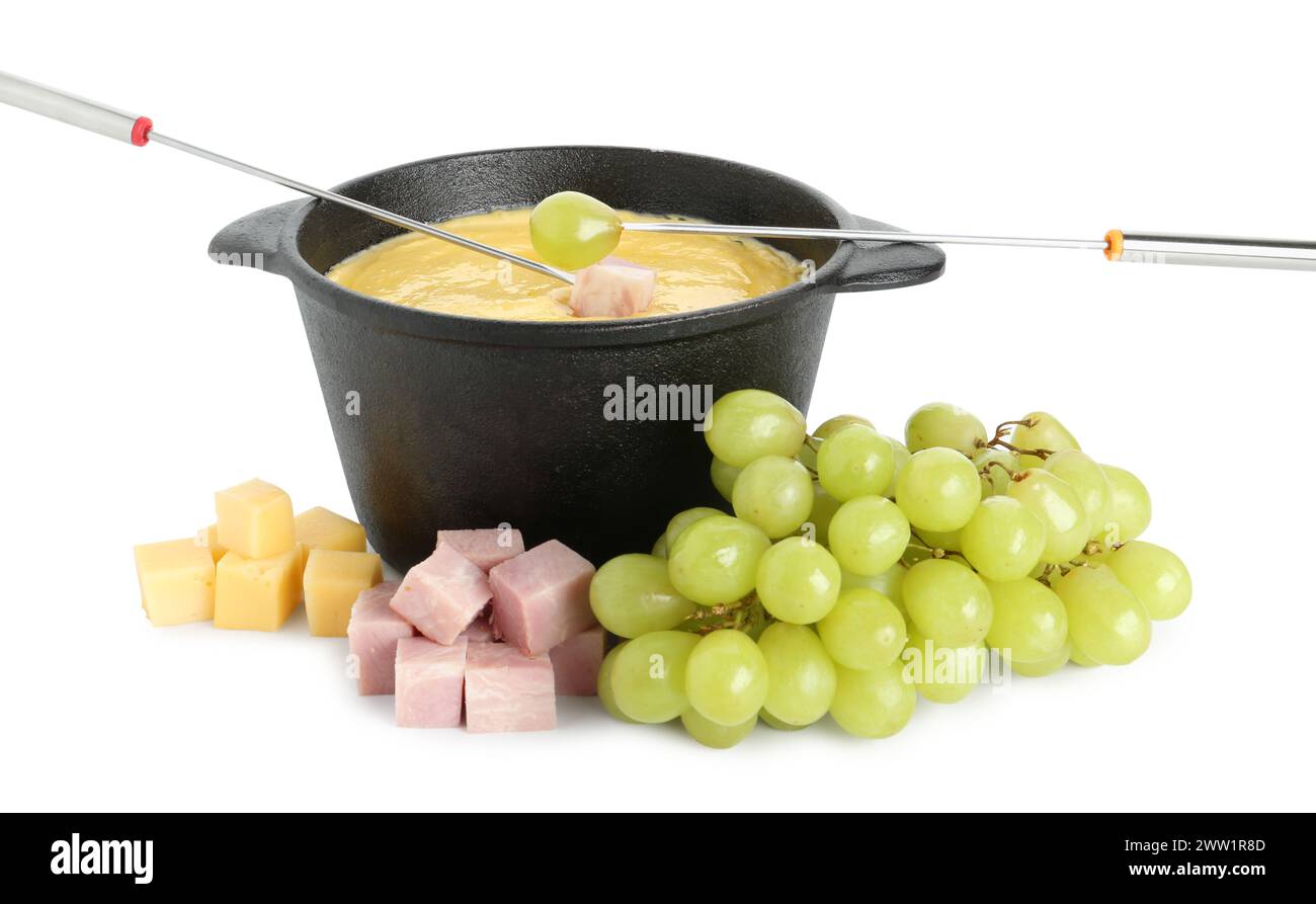 Tremper le raisin et le jambon dans un pot à fondue avec du fromage fondu savoureux isolé sur blanc Banque D'Images