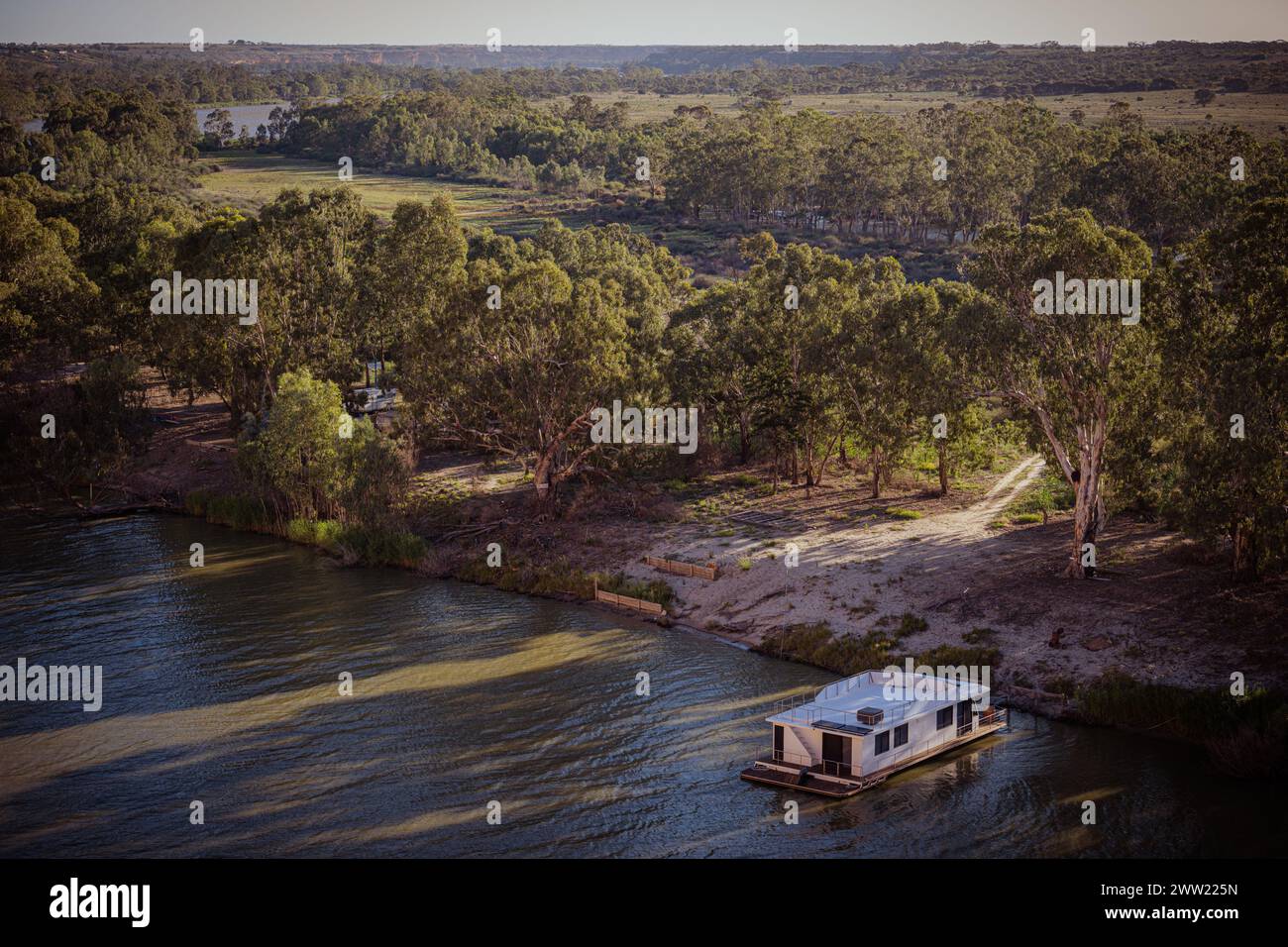 Une péniche flottant sur un paisible coude de rivière avec un environnement luxuriant. Banque D'Images