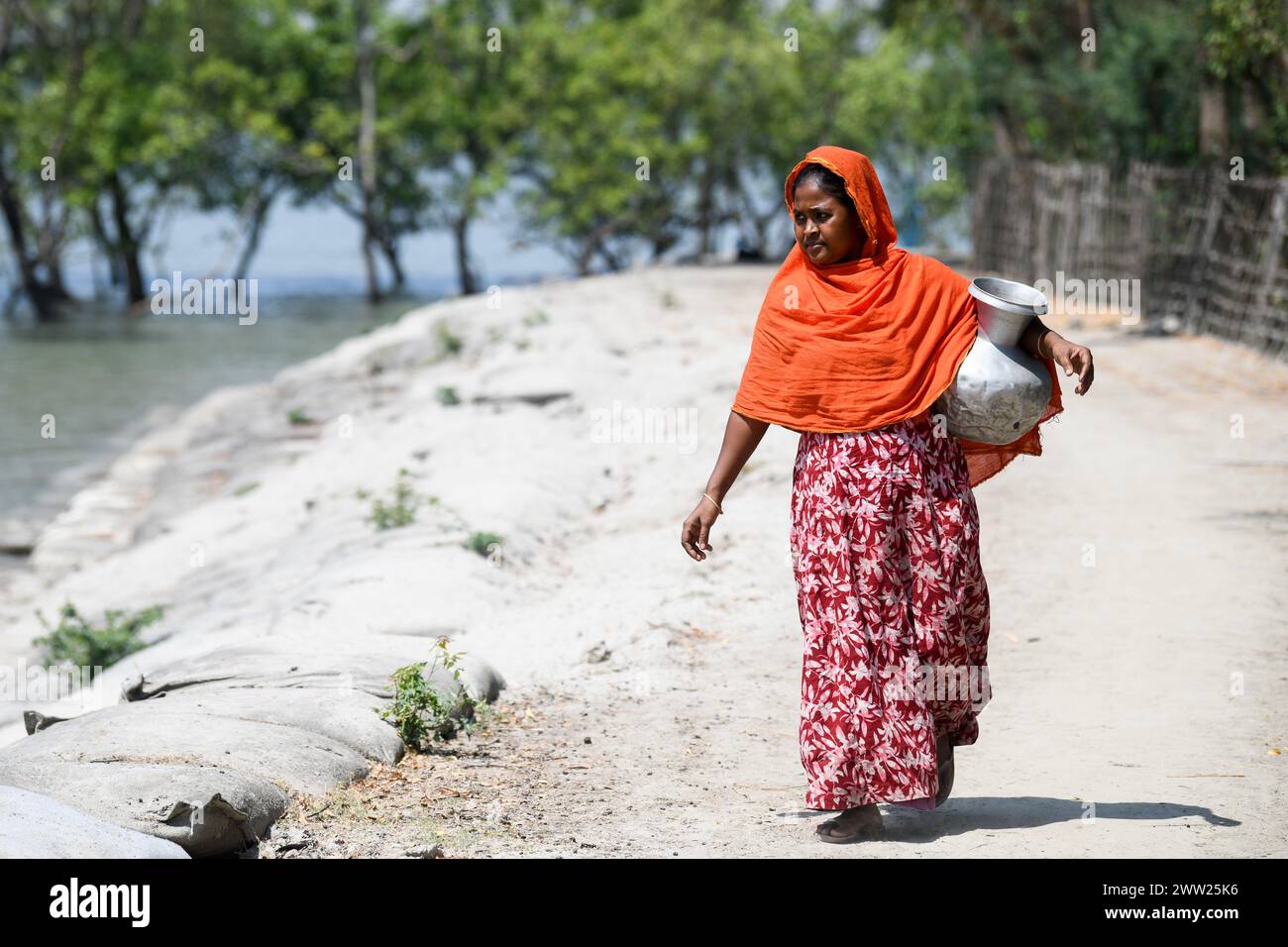 10 mars 2024, Dhaka, Bangladesh : une femme revient d’une station d’osmose inverse créée par une organisation non gouvernementale (ONG) locale à Shyamnagar Gabura dans le district de Satkhira. À Gabura Union, dans le district de Shatkhira, dans le sud du Bangladesh, les habitants sont confrontés à une grave crise de l’eau potable exacerbée par le changement climatique. Les gens, y compris les femmes et les enfants, doivent parcourir quotidiennement de longues distances pour accéder à des sources d'eau salubre, ce qui augmente les risques sanitaires liés aux maladies d'origine hydrique. Les données au niveau des districts côtiers mettent en évidence des pourcentages importants aux prises avec des pénuries d'eau, Banque D'Images