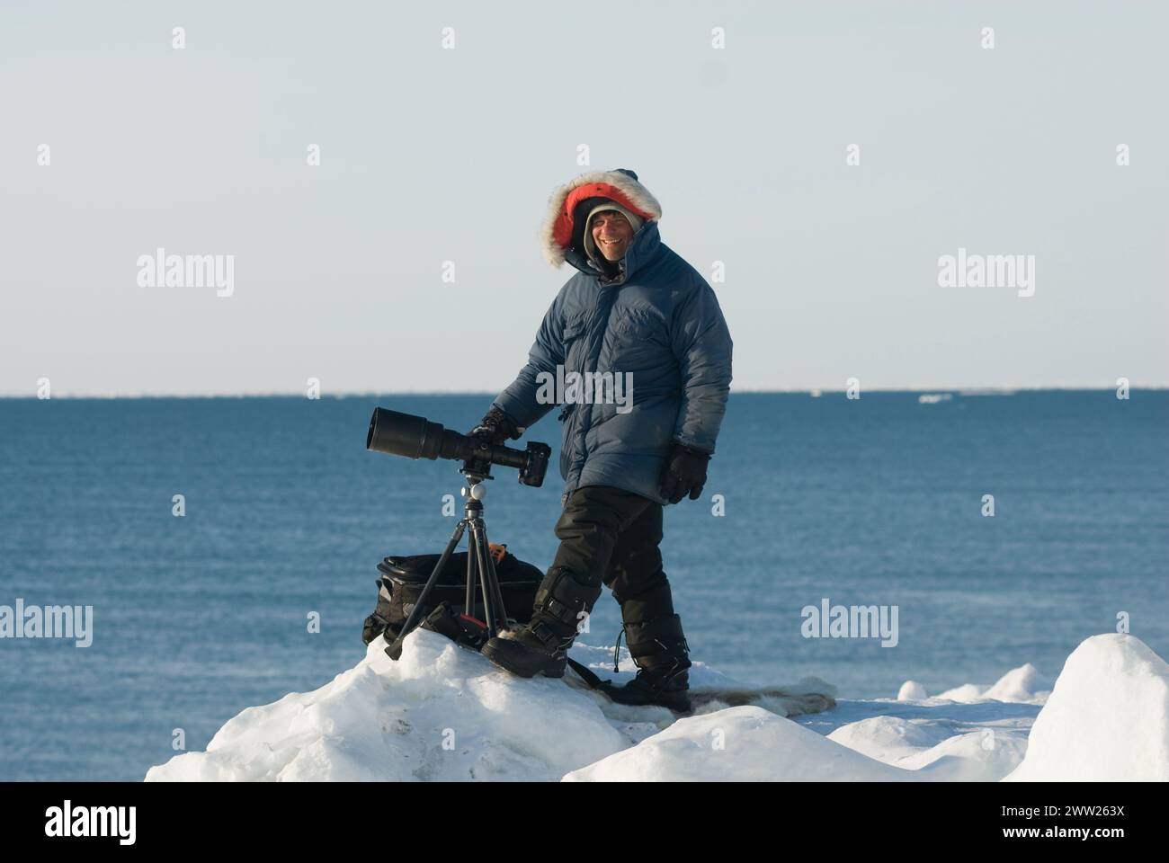 Photographe Steven Kazlowski avec appareil photo, trépied au bord d'une laisse ouverte dans la banquise, mer de Chukchi, au large de Barrow, Alaska Banque D'Images