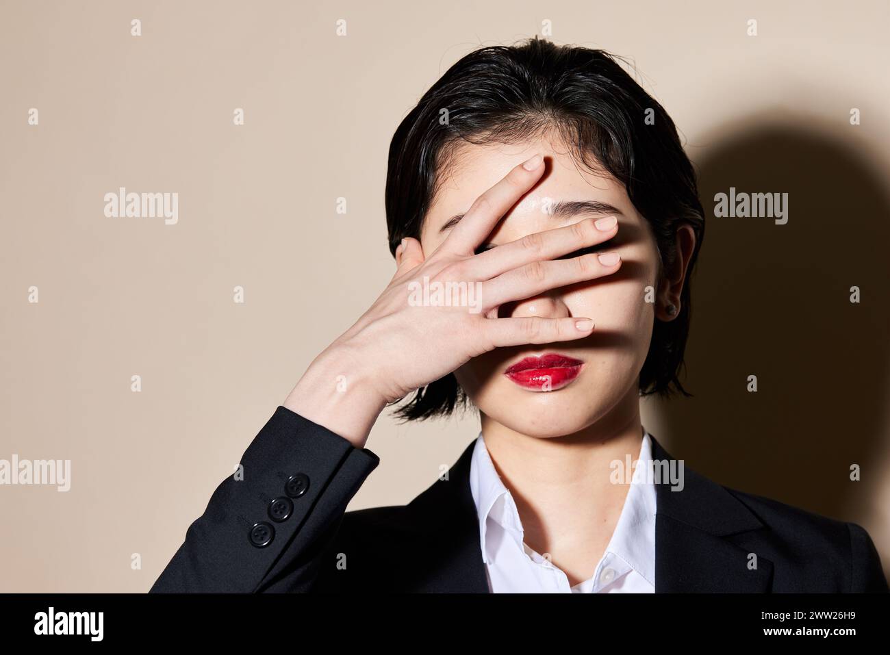 Une femme couvrant ses yeux avec sa main Banque D'Images