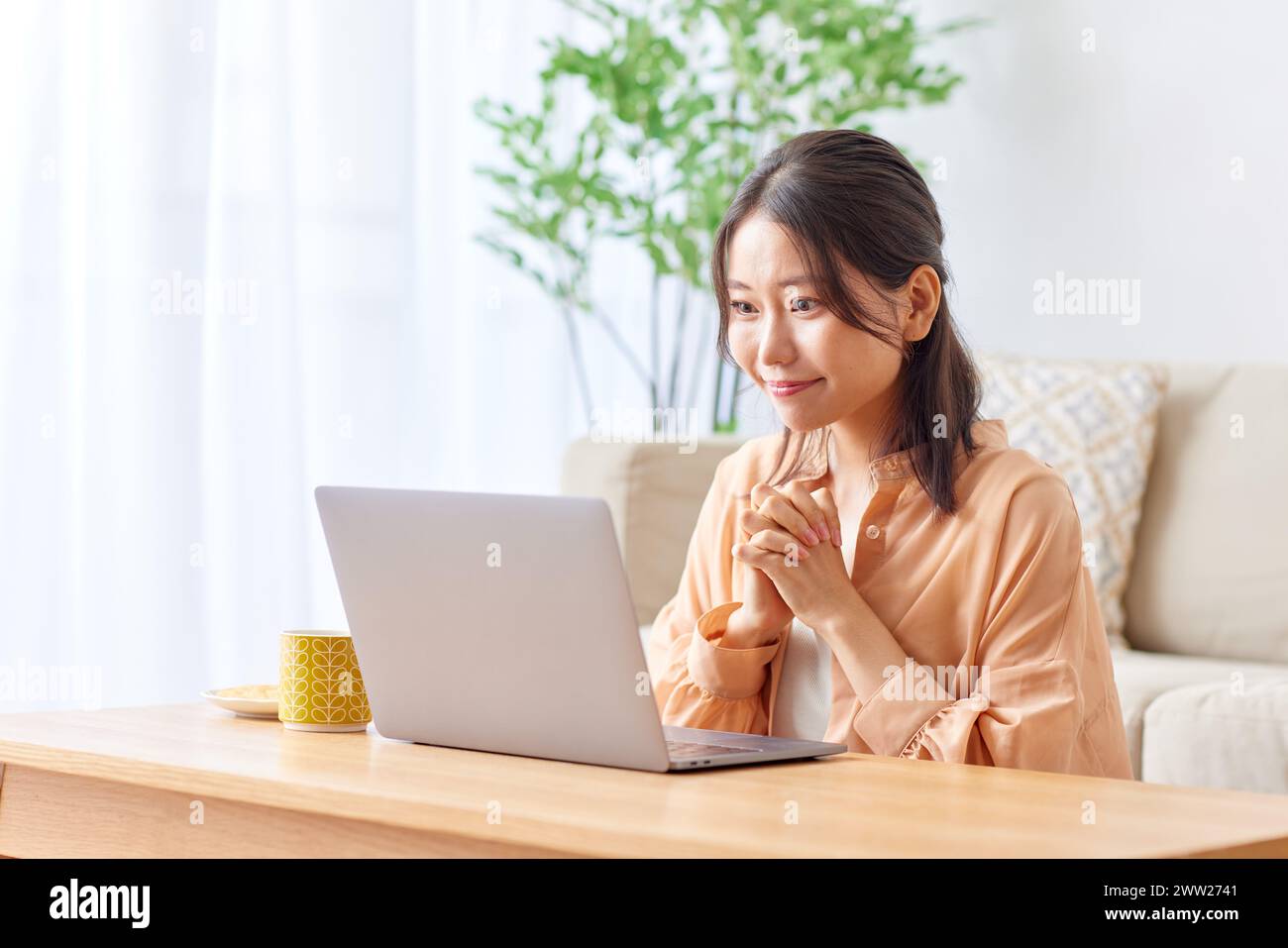 Asian woman using laptop in living room Banque D'Images