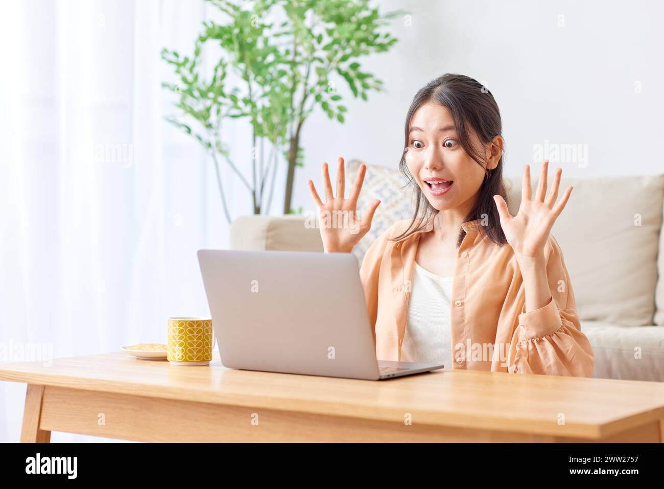 Une femme assise à une table, les mains levées Banque D'Images