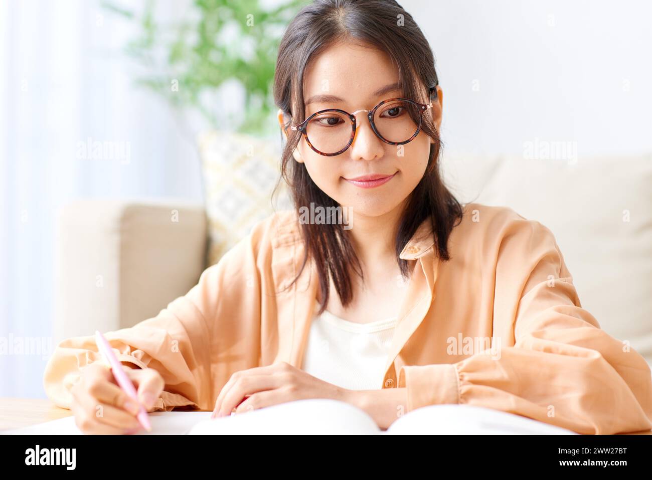 Une femme en lunettes écrivant sur un livre Banque D'Images