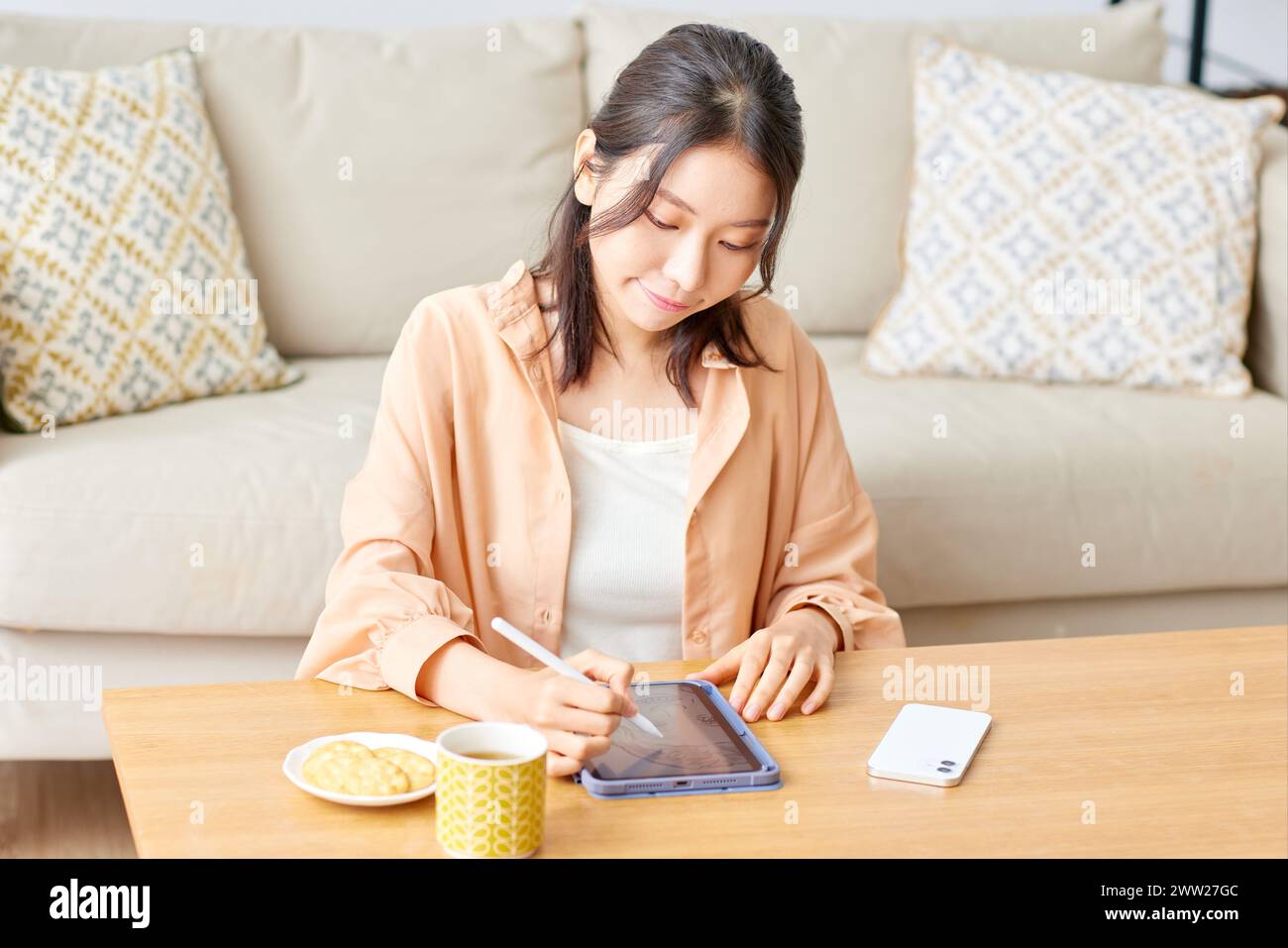 Une femme assise à une table avec une tablette et une tasse de café Banque D'Images