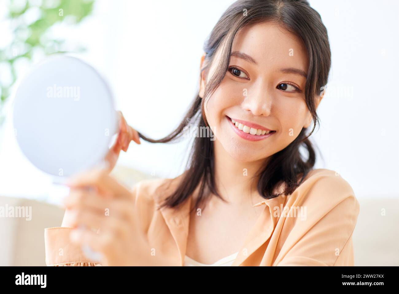 Femme asiatique souriant tout en tenant un miroir Banque D'Images