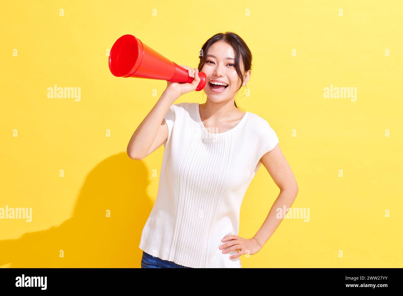 Femme asiatique tenant un mégaphone sur fond jaune Banque D'Images