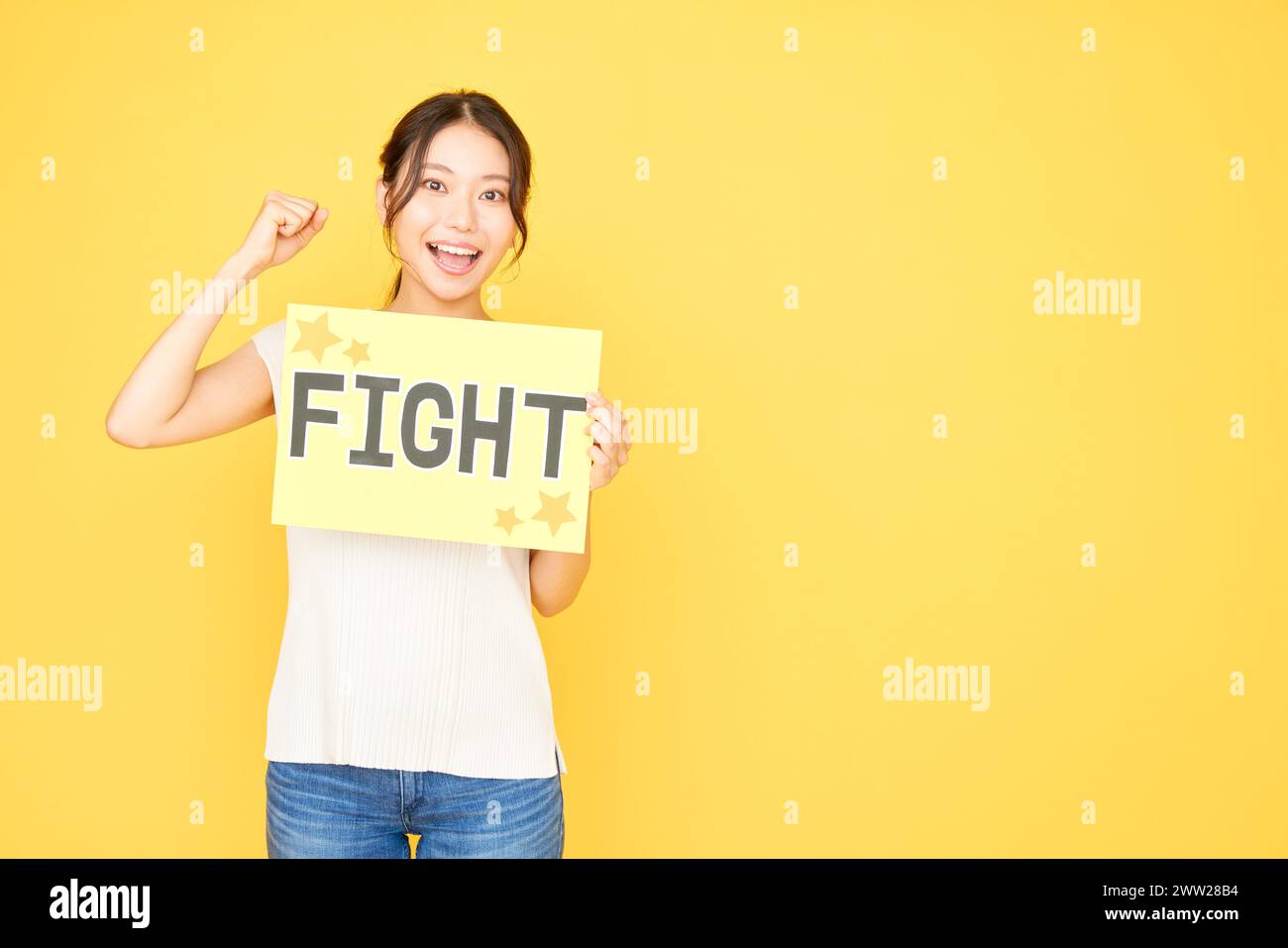 Femme tenant un signe de combat sur fond jaune Banque D'Images
