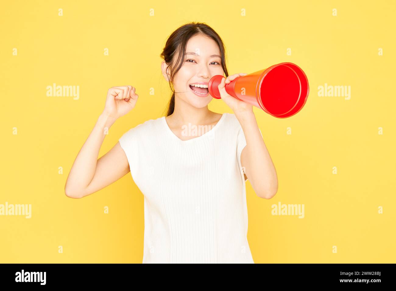 Femme asiatique criant dans un mégaphone sur fond jaune Banque D'Images