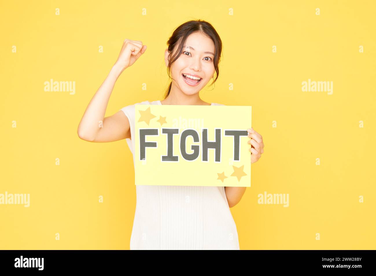 Femme tenant le signe de combat sur fond jaune Banque D'Images