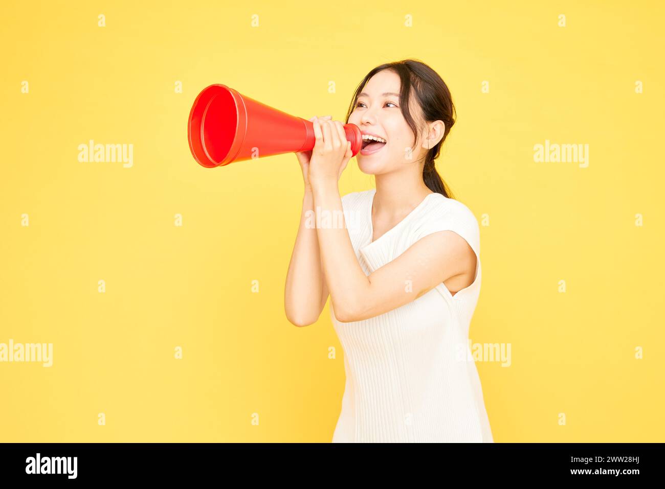 Une femme tenant un mégaphone rouge sur un fond jaune Banque D'Images