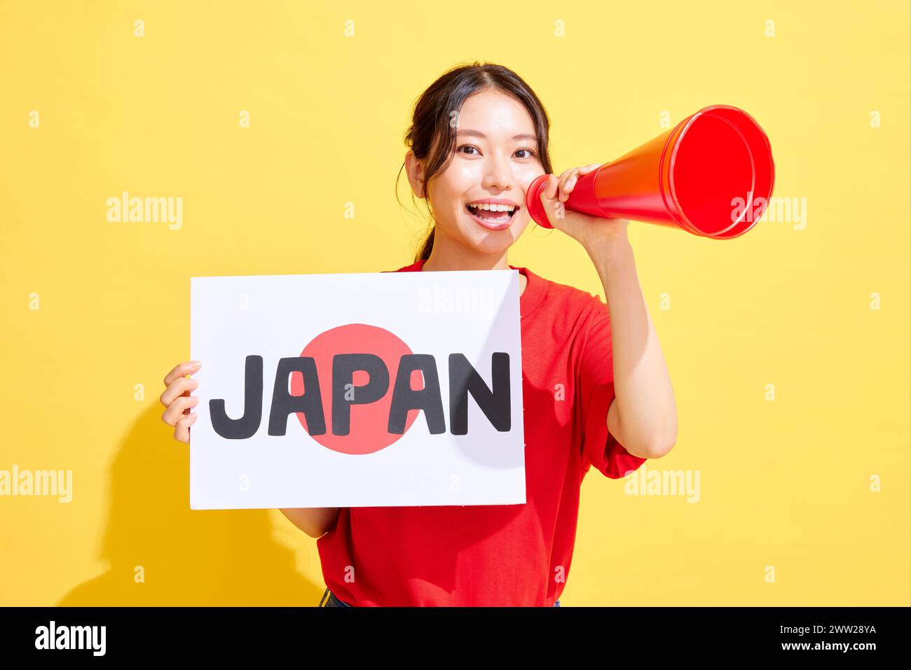 Femme japonaise tenant un tableau blanc et un mégaphone et acclamant Banque D'Images