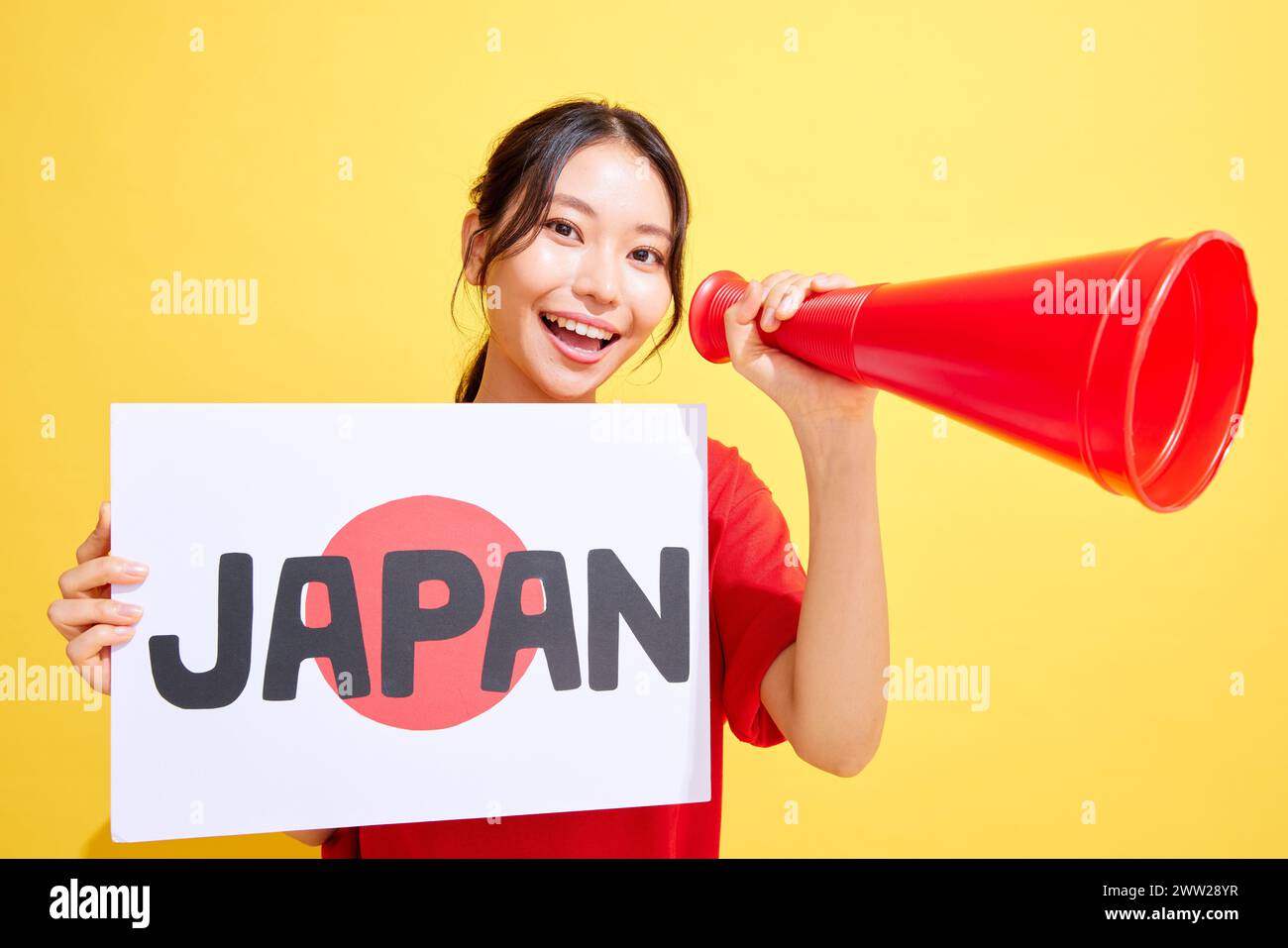 Femme japonaise tenant un tableau blanc et un mégaphone et acclamant Banque D'Images