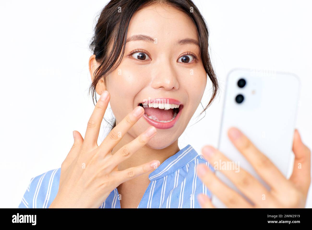 Une femme tenant son téléphone et faisant un visage surpris Banque D'Images