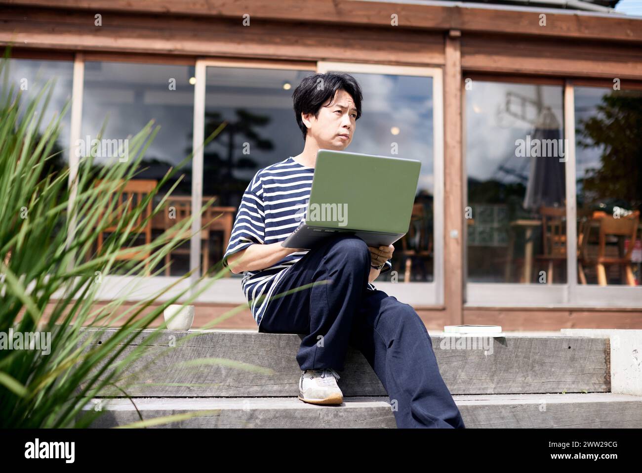 Un homme assis sur les marches avec un ordinateur portable Banque D'Images