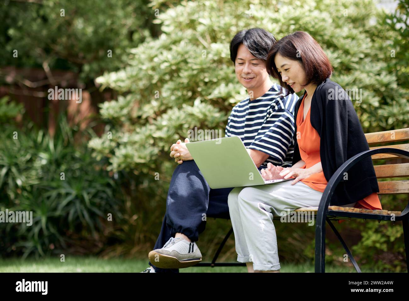 Couple asiatique utilisant un ordinateur portable dans le jardin Banque D'Images