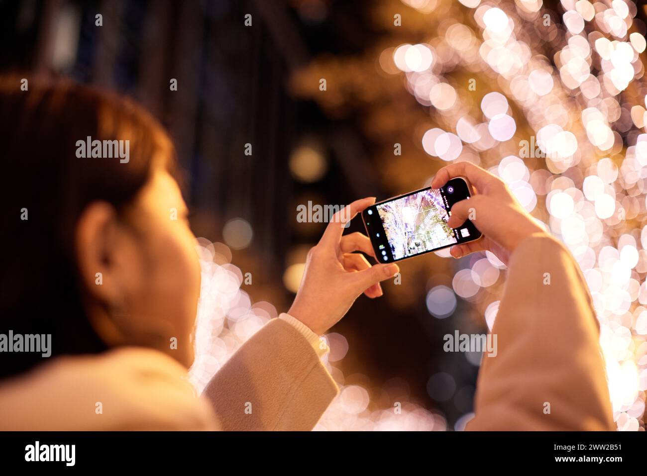 Une femme prenant une photo d'un sapin de Noël avec son téléphone Banque D'Images