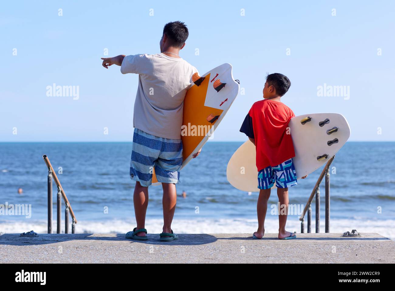 Famille avec planches de surf à la plage Banque D'Images