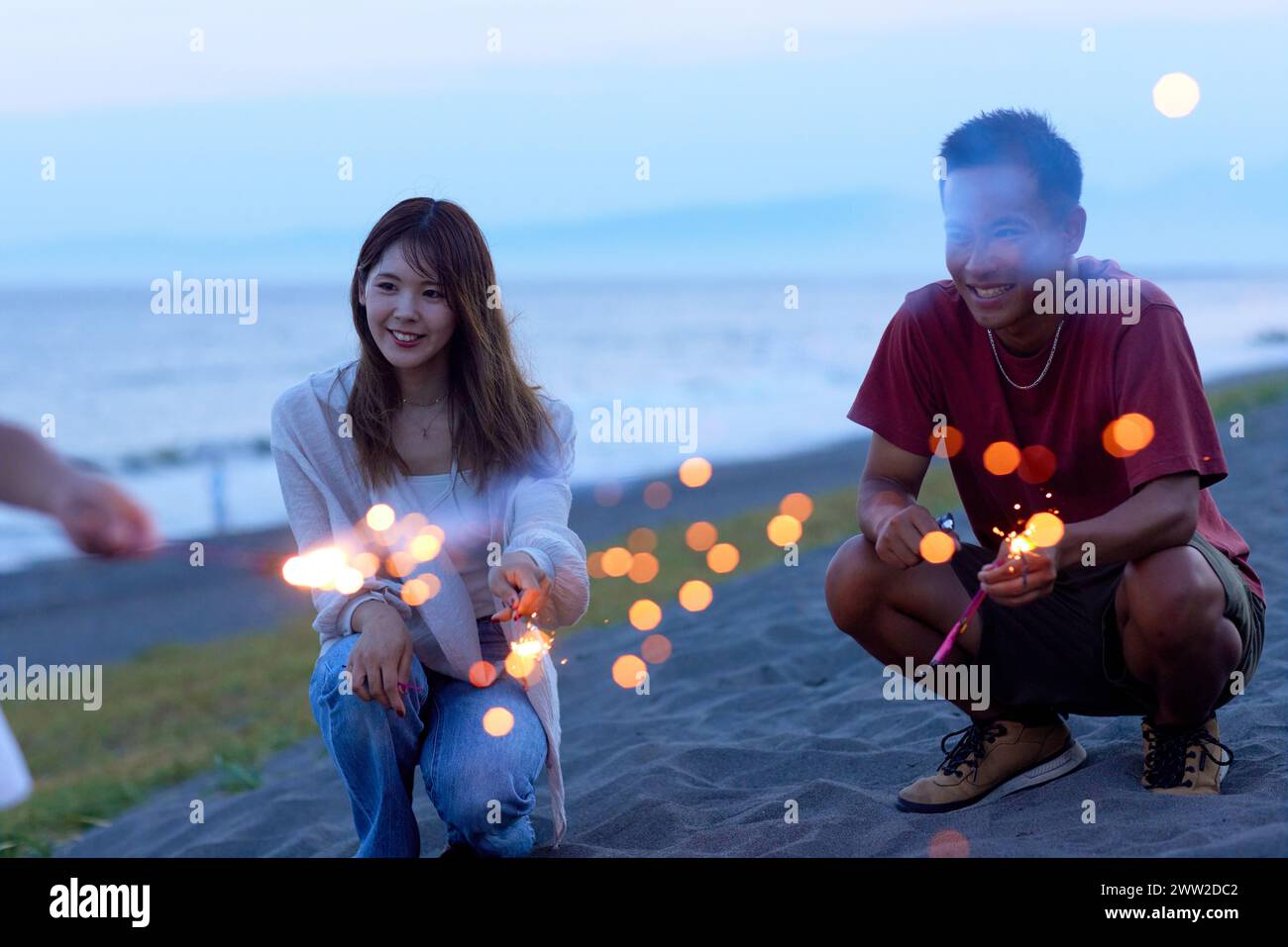 Un homme et une femme assis sur la plage avec des étincelles Banque D'Images