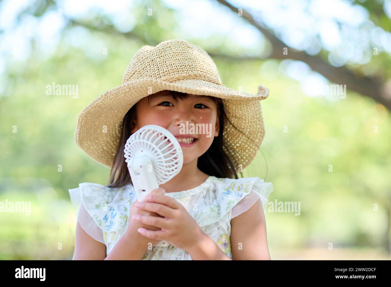 Une petite fille dans un chapeau tenant un éventail Banque D'Images