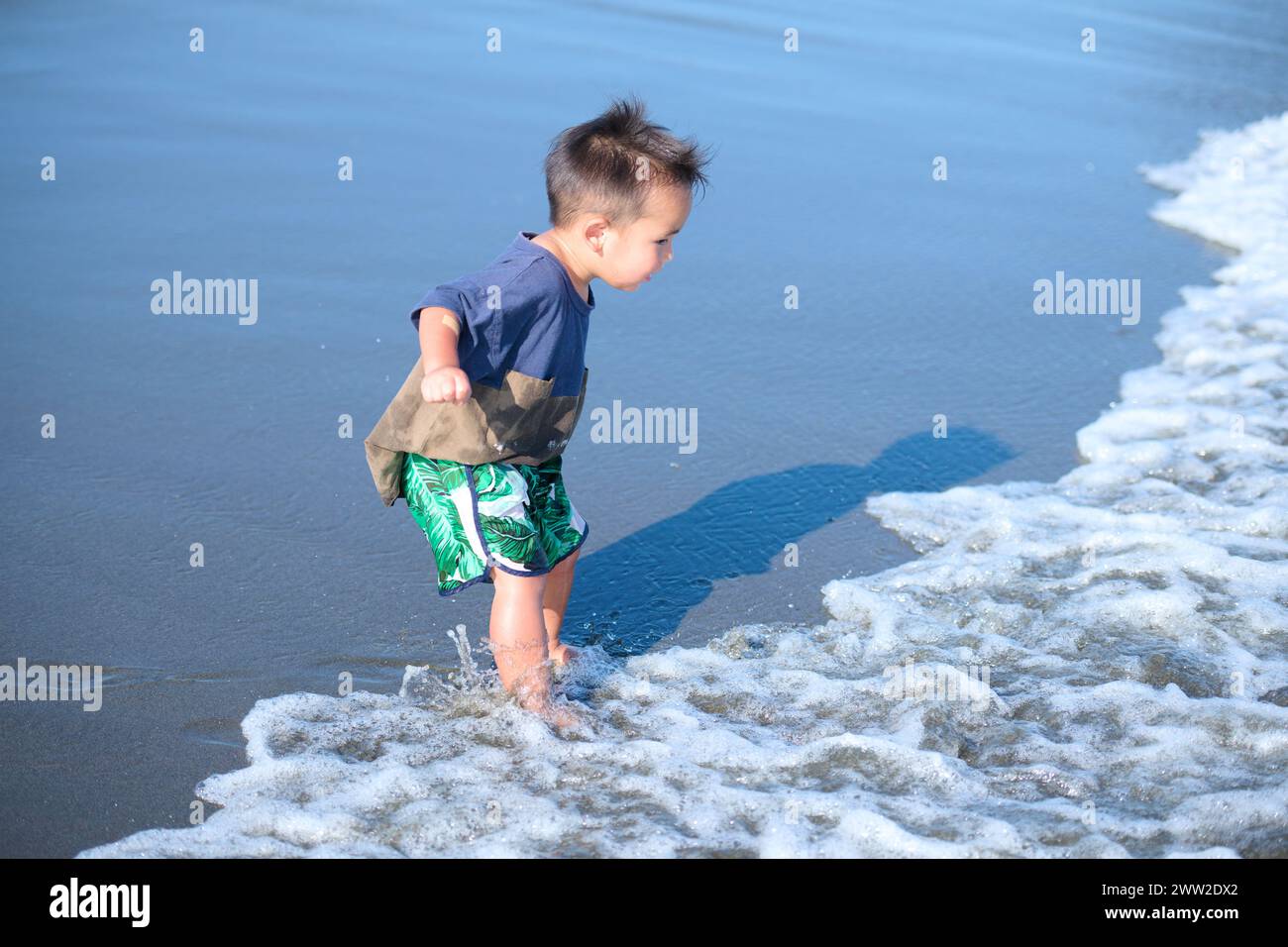 Un jeune garçon jouant à l'océan Banque D'Images