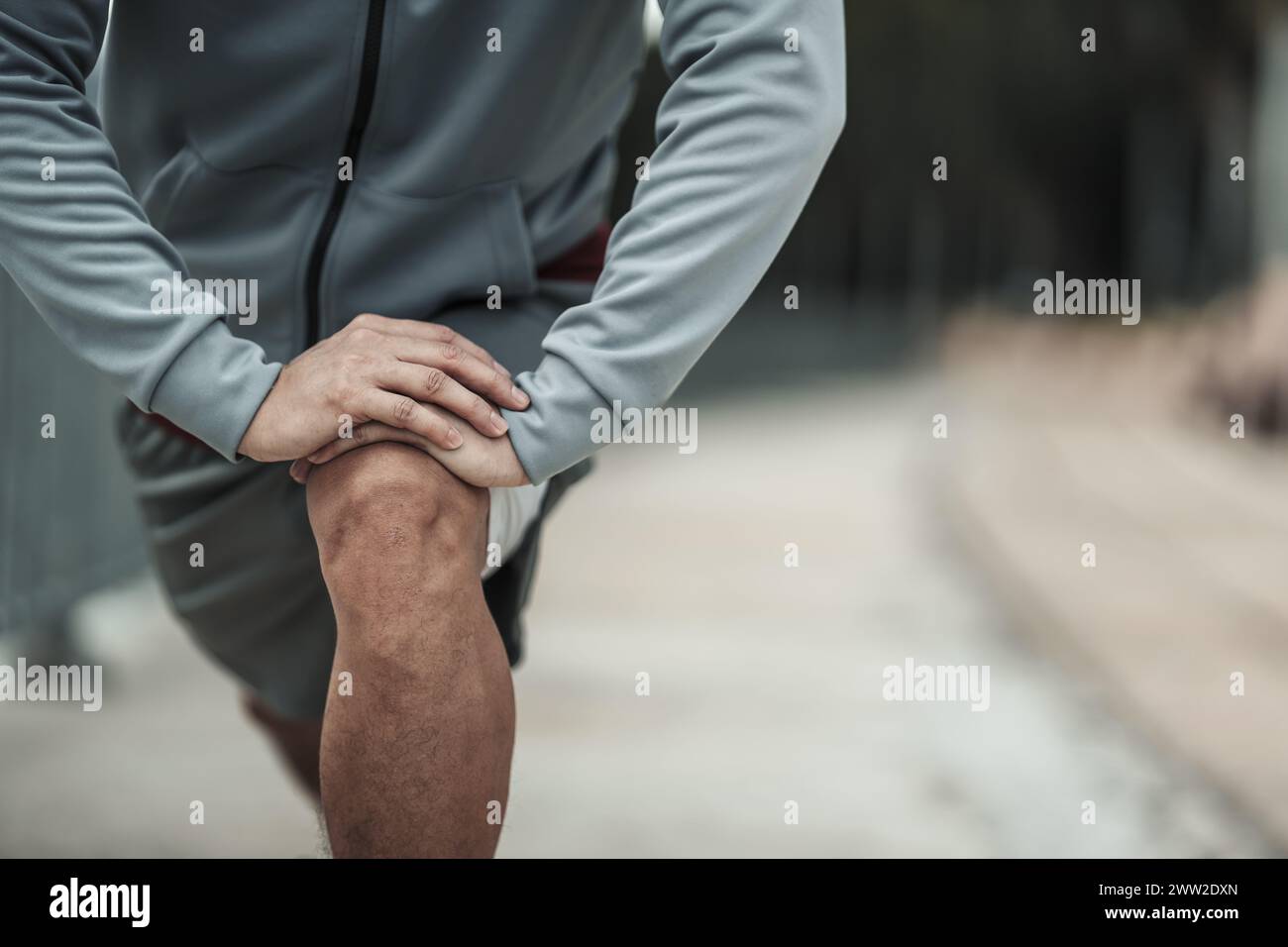Un homme étirant son muscle dans le parc du centre-ville avant l'entraînement cardio, la course. Santé et style de vie dans le concept de vie de grande ville. Banque D'Images