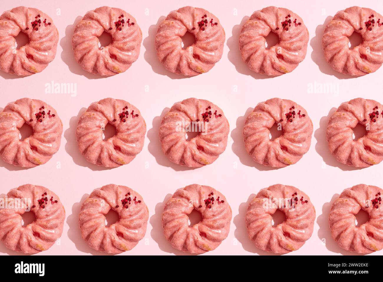 Un motif de beignets sur un fond rose Banque D'Images