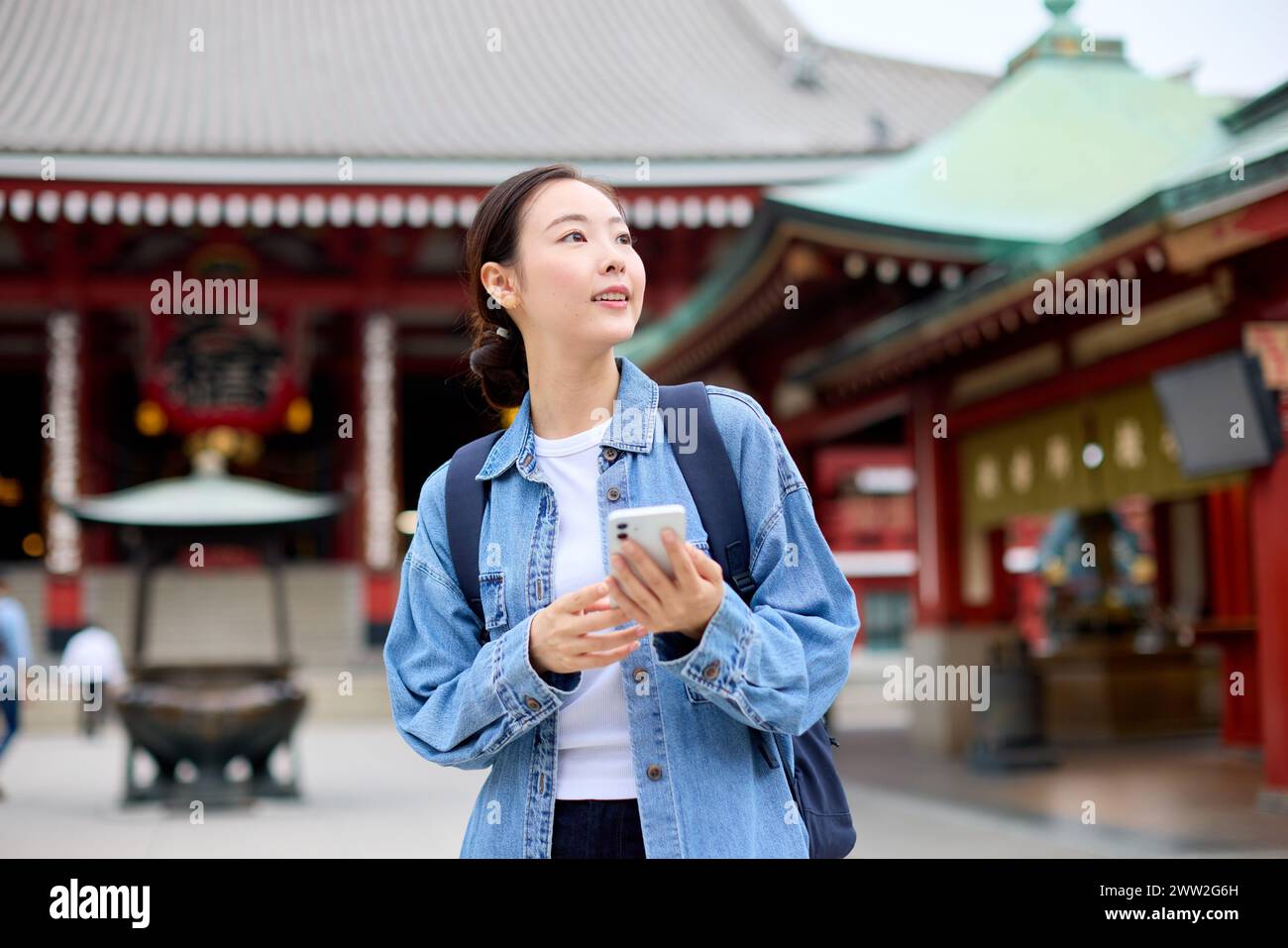 Une femme en veste denim regardant son téléphone Banque D'Images