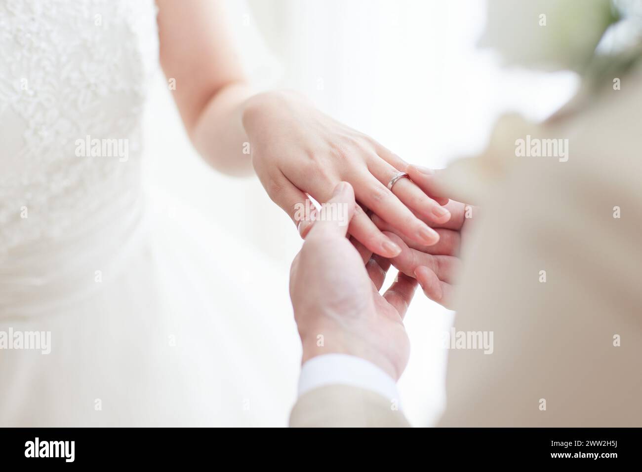 Un gros plan d'une mariée et mariée mettant leurs anneaux de mariage Banque D'Images