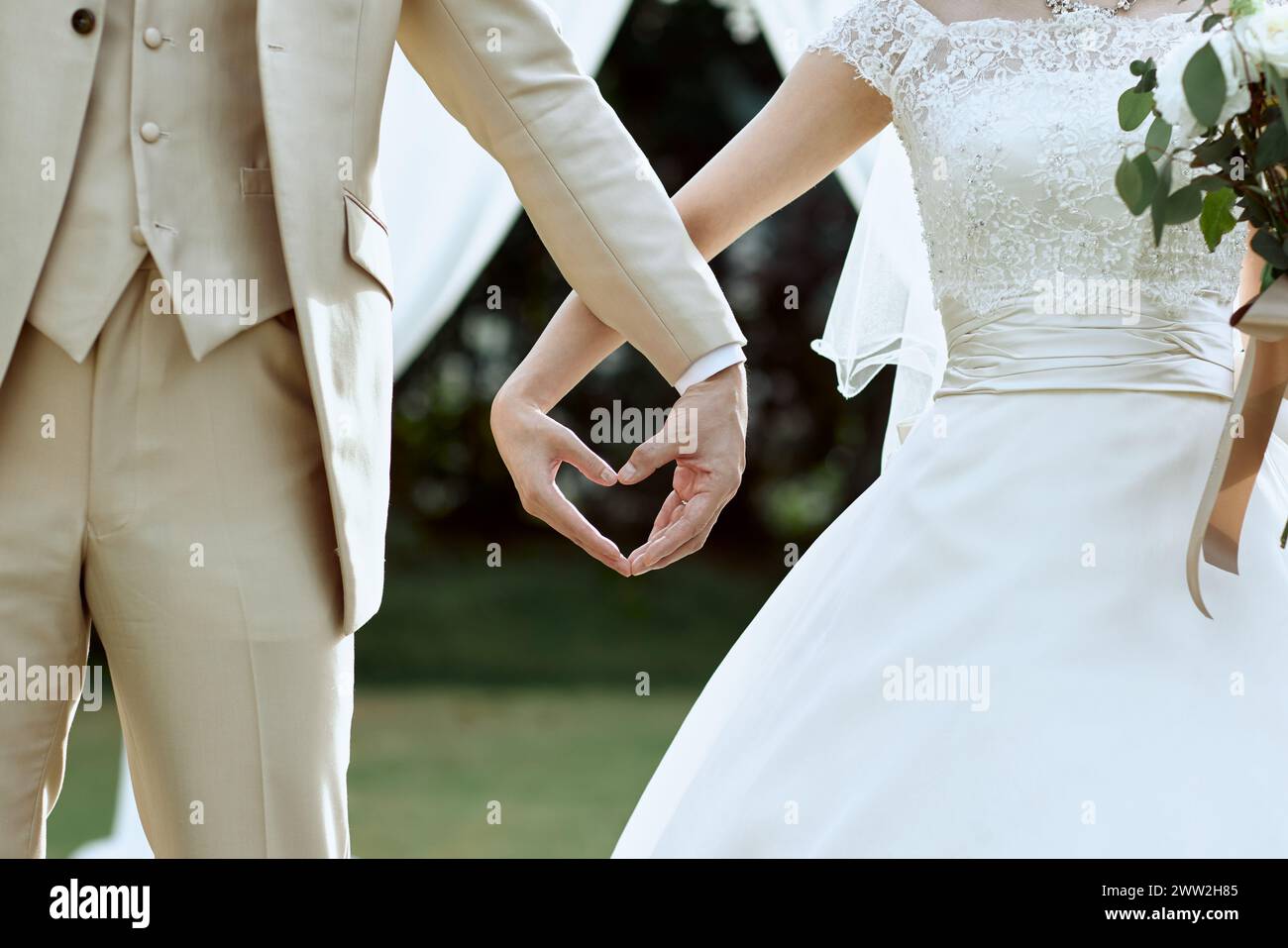 Une mariée et un marié tenant les mains dans une forme de coeur Banque D'Images