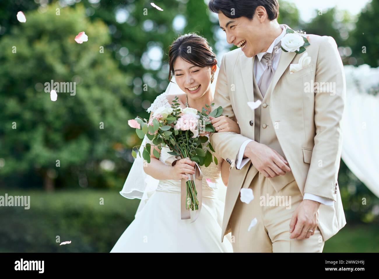 Un couple nouvellement marié marchant dans un champ avec des pétales tombant Banque D'Images
