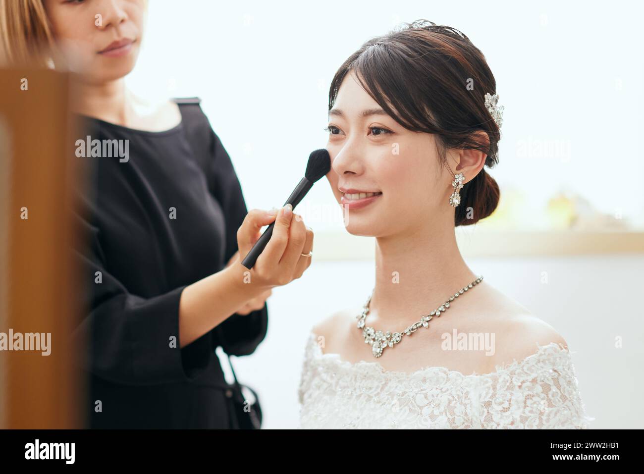 Une femme dans une robe de mariée se maquillant Banque D'Images