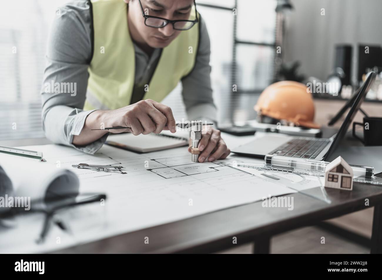 Les mains d'architecture tiennent le pied à coulisse à vernier travaillant et vérifiant l'échelle de tuyau de joint avec la planification de salle de bain. Concept d'architecture et d'ingénieur. Banque D'Images