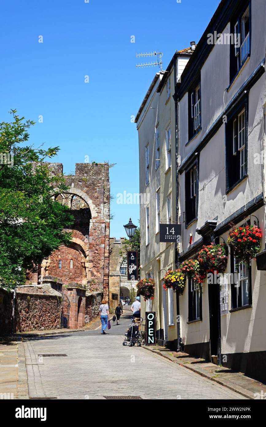Vue sur le château de Rougemont (également connu sous le nom de château d'Exter) gatehouse ruines dans le centre-ville avec un café à droite, Exeter, Devon, Royaume-Uni, Europe. Banque D'Images