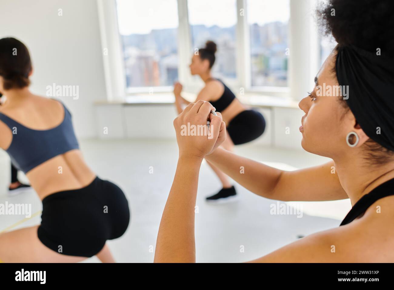 focus sur la femme afro-américaine exerçant à côté de sportives floues pendant le cours de pilates Banque D'Images