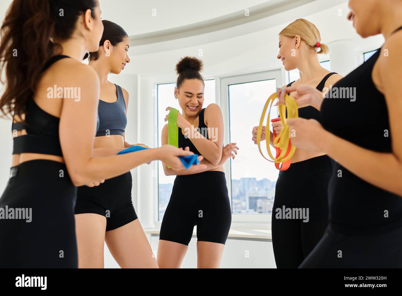 groupe de femmes sportives diverses heureuses tenant des bandes de résistance et riant après l'entraînement pilates Banque D'Images