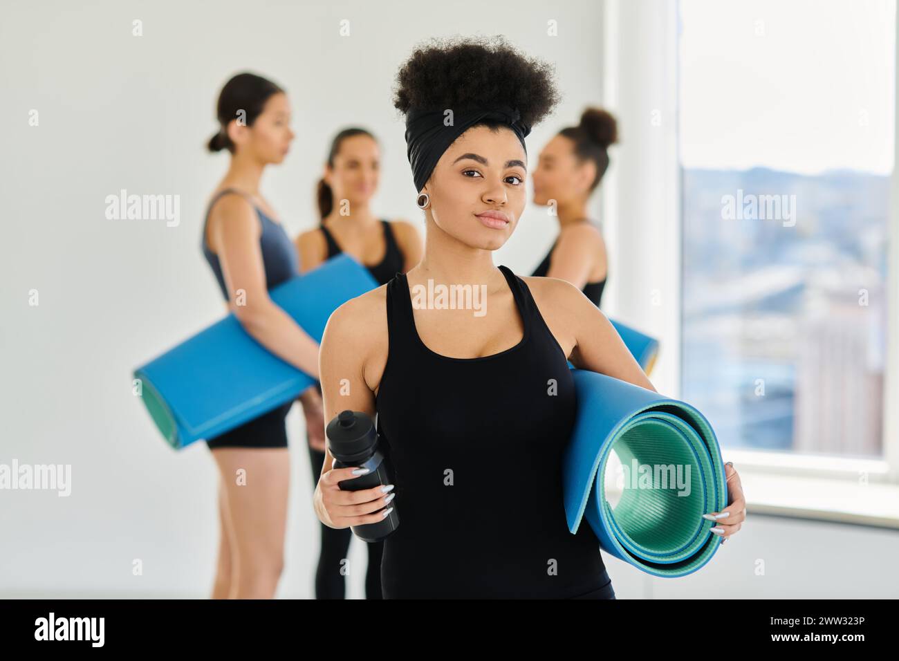 focus sur la femme afro-américaine debout avec tapis de fitness et bouteille de sport dans le studio de yoga Banque D'Images