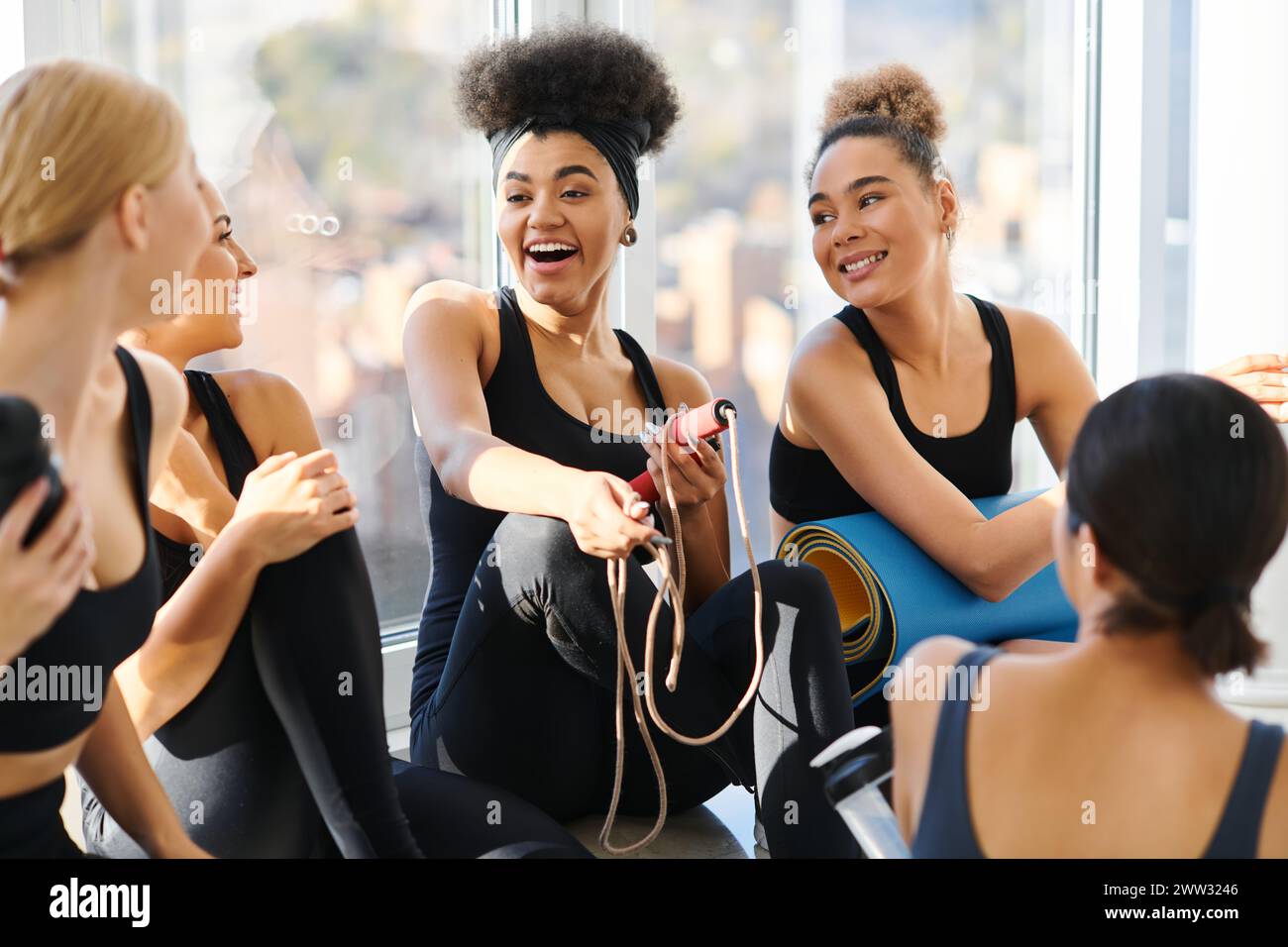 groupe de jeunes femmes interraciales heureuses en vêtements actifs discutant après l'entraînement dans le studio de pilates Banque D'Images