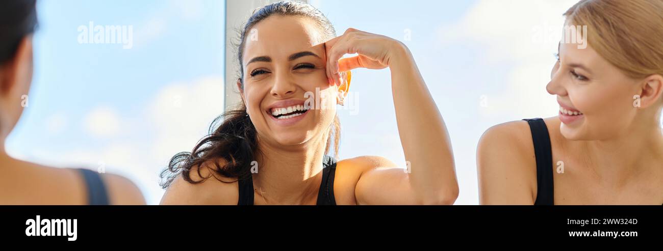 lumière du soleil sur le visage de la femme brune heureuse en vêtements actifs riant après l'entraînement avec des amis, bannière Banque D'Images