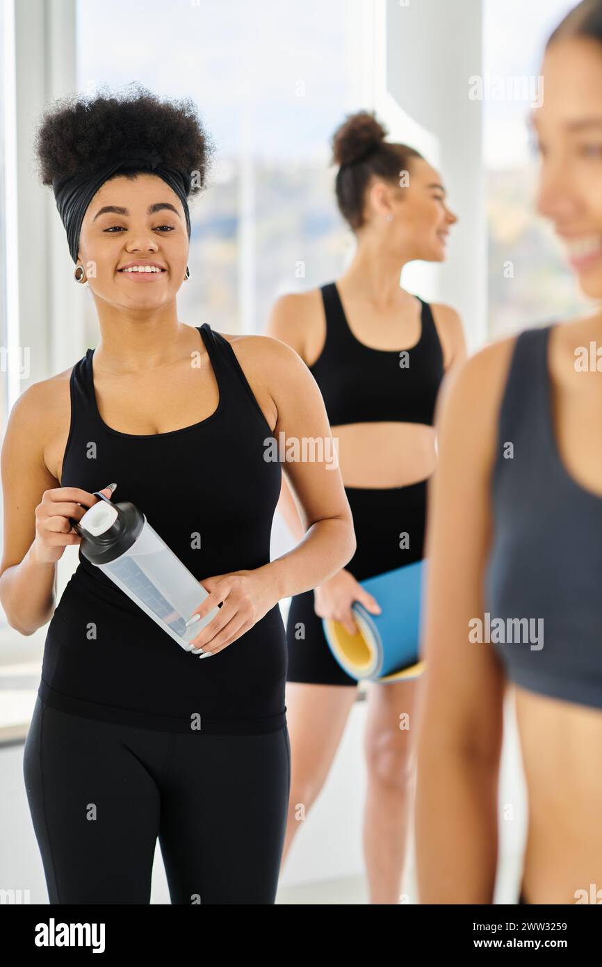 concentrez-vous sur la femme afro-américaine heureuse regardant ses amis flous après l'entraînement dans le studio de pilates Banque D'Images