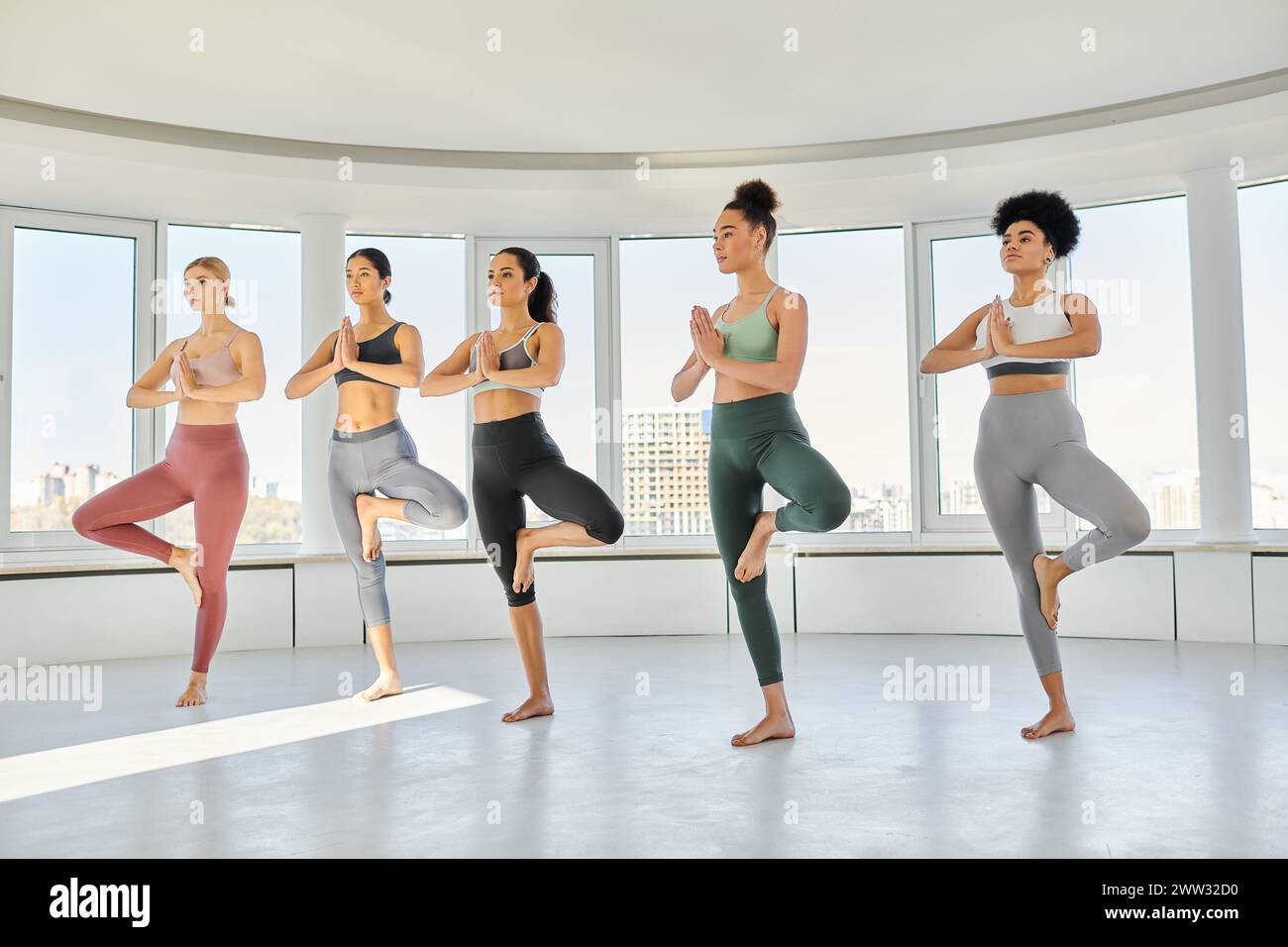 groupe de jeunes cinq femmes diverses dans les vêtements de sport pratiquant l'exercice de yoga ensemble en studio Banque D'Images
