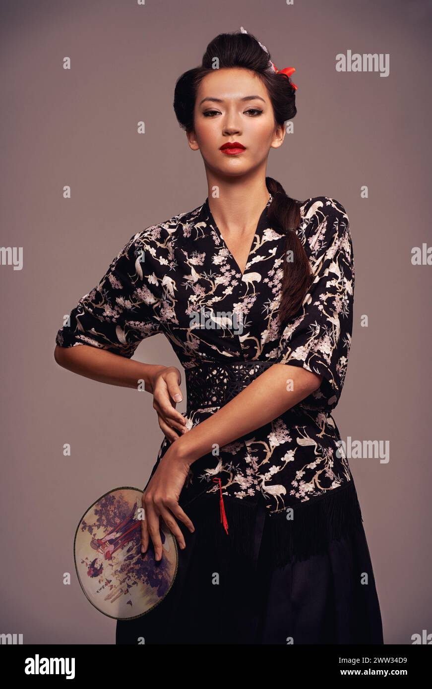 Femme asiatique, traditionnelle et mode avec miroir à main en studio sur fond brun dans la confiance, le style et élégant. Portrait, personne féminine et Banque D'Images